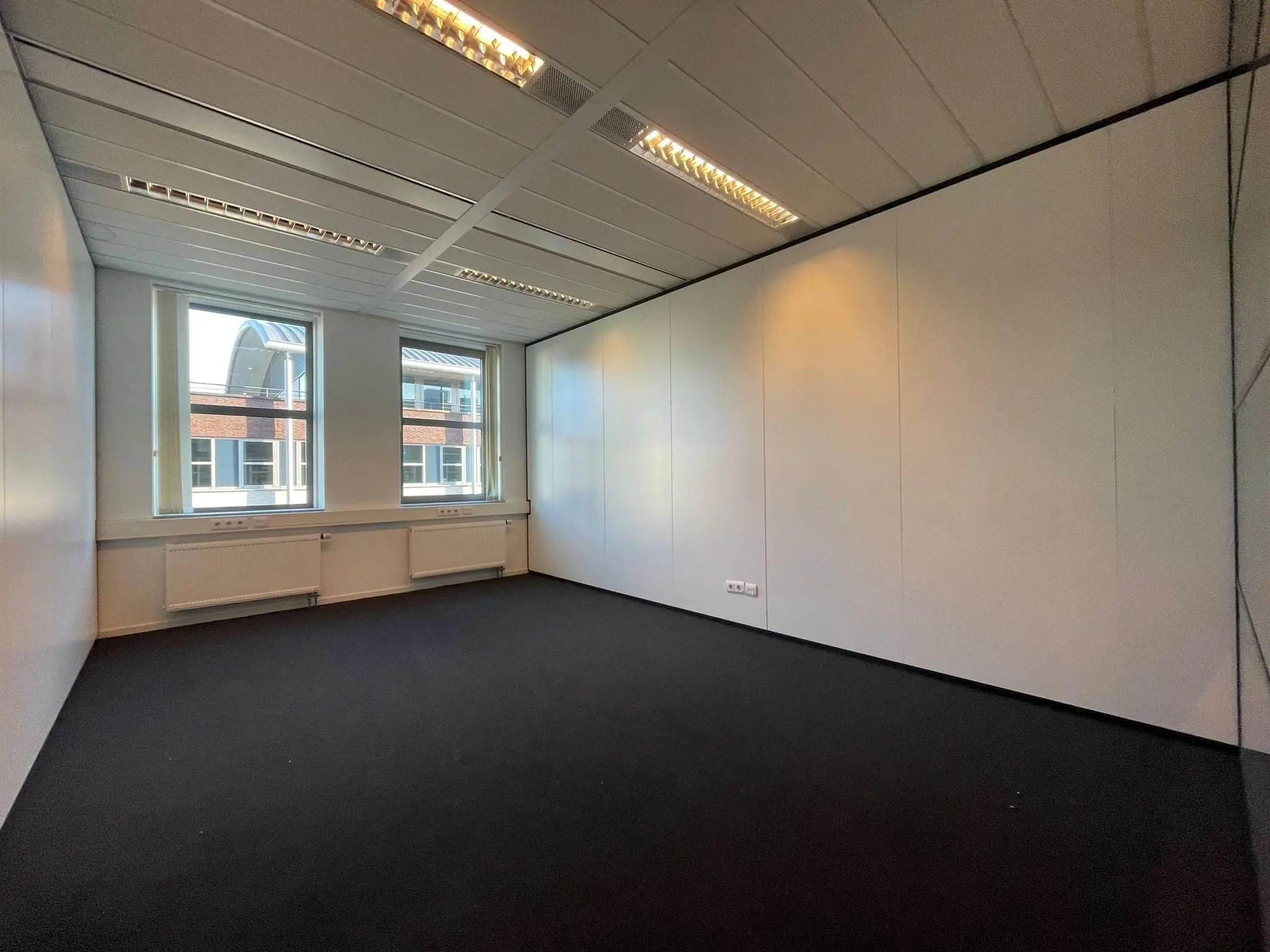 Leeg, modern kantoor met twee ramen en witte wanden in bedrijfsverzamelgebouw De Wel.